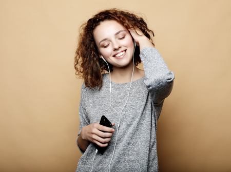 lifestyle and people concept: young woman in headphones listening to music smiling with closed eyes...