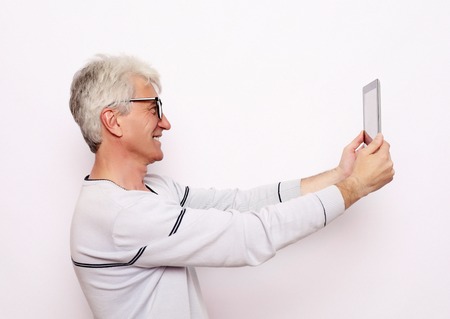 Gray-haired elderly man communicates with his family on a tabletの写真素材