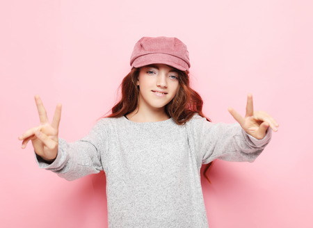 happy people concept - smiling little curly girl showing peace gesture with fingers, close upの写真素材