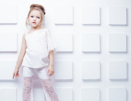 Cute little blond girl wearing white casual clothes on a white background. Fashion style.の写真素材