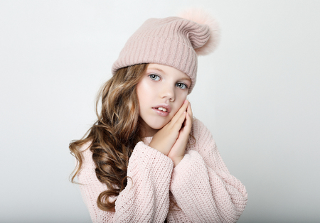 People, childhood and fashion concept: little girl child wearing pink winter hat and sweater over pink backgroundの写真素材