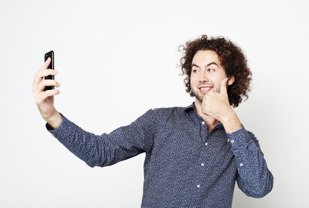 Portrait of a cheerful  man taking selfie over white backgroundの写真素材