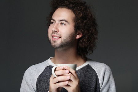 Taking a coffee break. Handsome young man holding coffee cupの写真素材