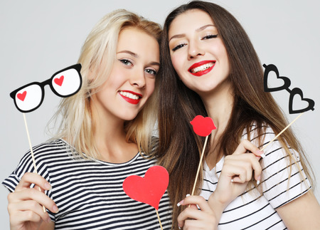 two stylish sexy  girls best friends holding paper party sticksの写真素材