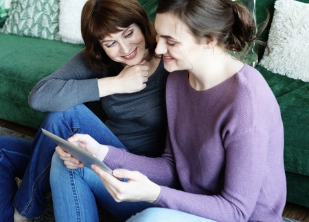 mother and adult daughter using tablet computer at homeの写真素材