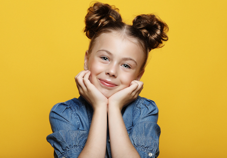 Portrait of cheerful smiling little girl on yellow backgroundの写真素材