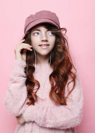 Image of happy teen girl standing isolated on pink background, in pink hat and sweater.の写真素材