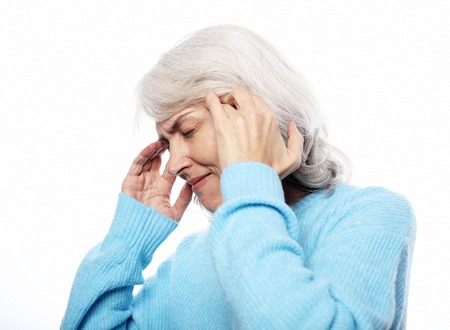 portrait of a senior lady having headache over white backgroundの写真素材