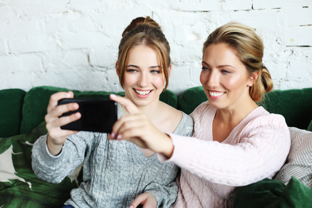 mature mother and her daughter making a selfie using smart phoneの写真素材