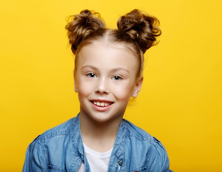Portrait of cheerful smiling little girl on yellow backgroundの写真素材