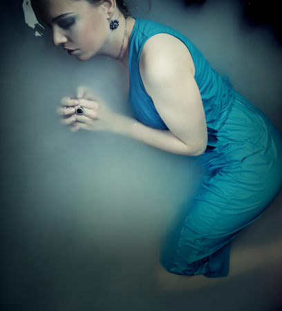 woman in blue dress lying in waterの写真素材