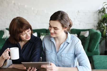 mother and adult daughter using tablet computer at homeの写真素材