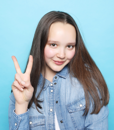 happy girl  looking at camera with smile and showing peace sign with fingersの写真素材