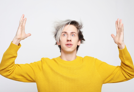 attractive man wearing yellow sweater astonished and amazed in shock and surprise face expression