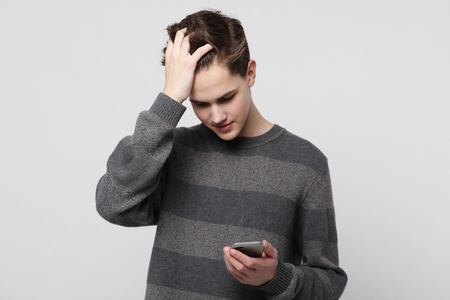 Happy young man typing sms on white backgroundの写真素材
