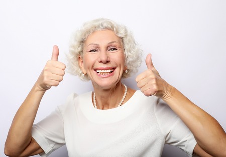 Elderly woman giving a thumb up and looking at the cameraの写真素材