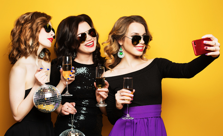 Close-up shot of group of laughing girls having party, take selfie with smartphoneの写真素材