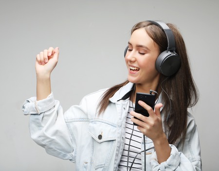Beautiful young woman listening to music in headphones with smartphoneの写真素材