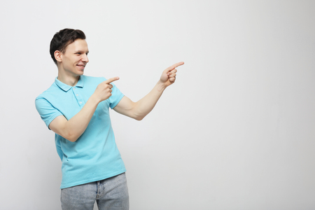 Positive man looks and points at upper right corner with both index fingersの写真素材