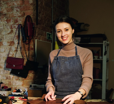 woman works in a bag making studio, cuts out details