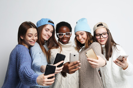 african-american and caucasian  women, holding looking on smartphones. Chatting in social networks online.の写真素材