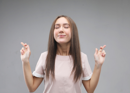 Joyful young female, raises fingers crossed, makes desirable wish.の写真素材