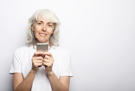 ifestyle, family and people concept: old grandmother is talking to her grandchildren by phone, smiling and greeting themの写真素材