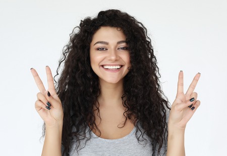 Photo of american woman looking on camera and showing peace sign isolated over white background, close upの写真素材
