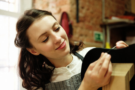 young woman works in a bag making studio, cuts out details