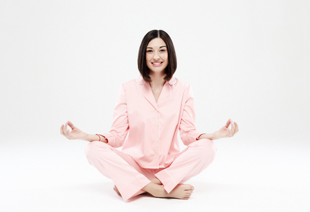 beautiful girl dressed in pink pajamas meditatesの写真素材
