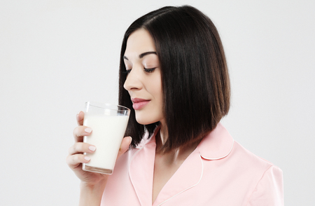 lifestyle and people concept: beautiful girl dressed in pajamas drinking milkの写真素材