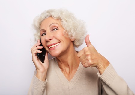technology, communication age and people concept: happy senior woman with smartphone over white background,の写真素材