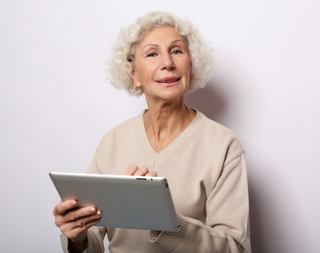 lifestyle, technology and people concept: Happy mature woman using a tablet, communicates with childrenの写真素材