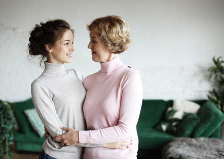 lifestyle, family and people concept: Happy young woman and her mother at homeの写真素材