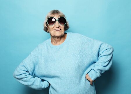 lifestyle and people concept - portrait of a content senior lady wearing blue sweater smiling and...