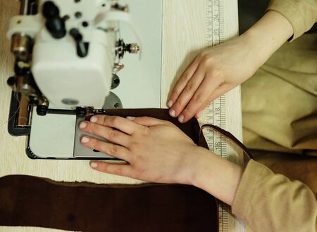 Closeup on young woman sewing leather handbagの写真素材