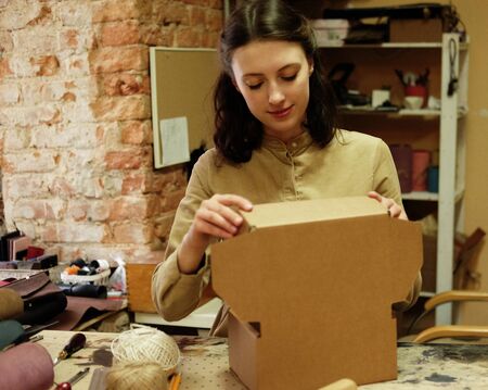 young woman folds packing box in sewing workshopの写真素材