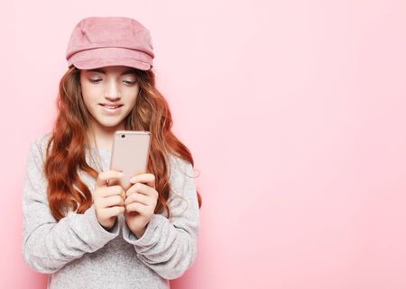 People, technology and internet concept - little girl kid with smartphone over pink background
