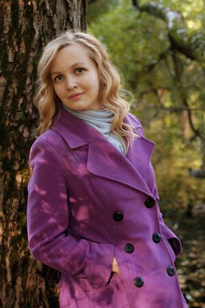 smiling woman in season warm clothing in autumn parkの写真素材