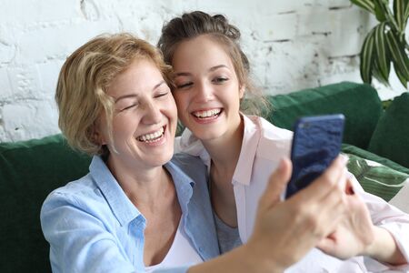 lifestyle, family, technology and people concept: mature mother and her daughter making a selfie using smart phoneの写真素材