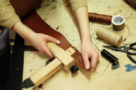 young brunette woman works in a bag making studio, cuts out details