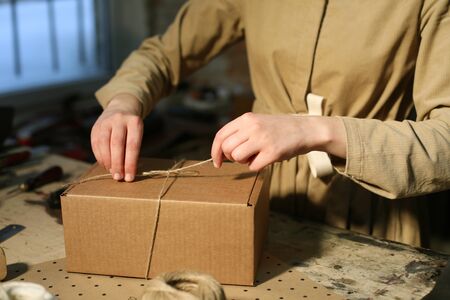 young woman folds packing box in sewing workshop