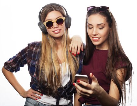tehnology, emotion and people concept: happy best girlfriends making selfie on smartphone over white backgroundの写真素材
