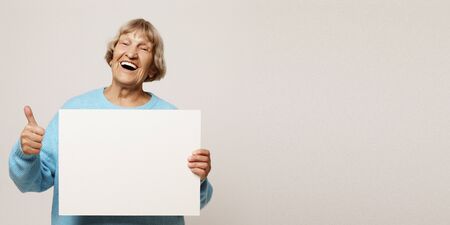 Aged woman with blank advertising board or copy spacet.