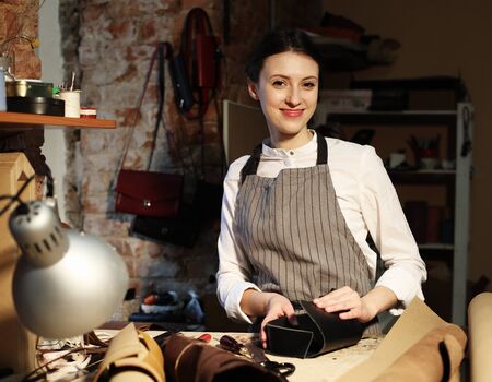 young brunette woman works in a bag making studio, cuts out detailsの写真素材