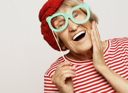 lifestyle, emotion and people concept: funny grandmother with fake glasses, laughs and ready for partyの写真素材