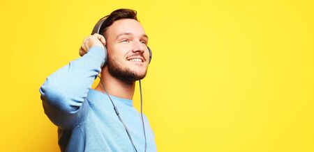 Handsome Man lictening to music over yellow backgroundの写真素材