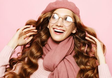 beautiful young female model with long wavy hair wearing pink beret , scarf and eyeglassesの写真素材
