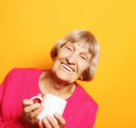 Portrait of old excited lady smiling laughing, holding cup drinking coffee, teaの写真素材