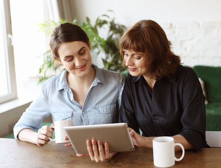 mother and adult daughter using tablet computer at homeの写真素材